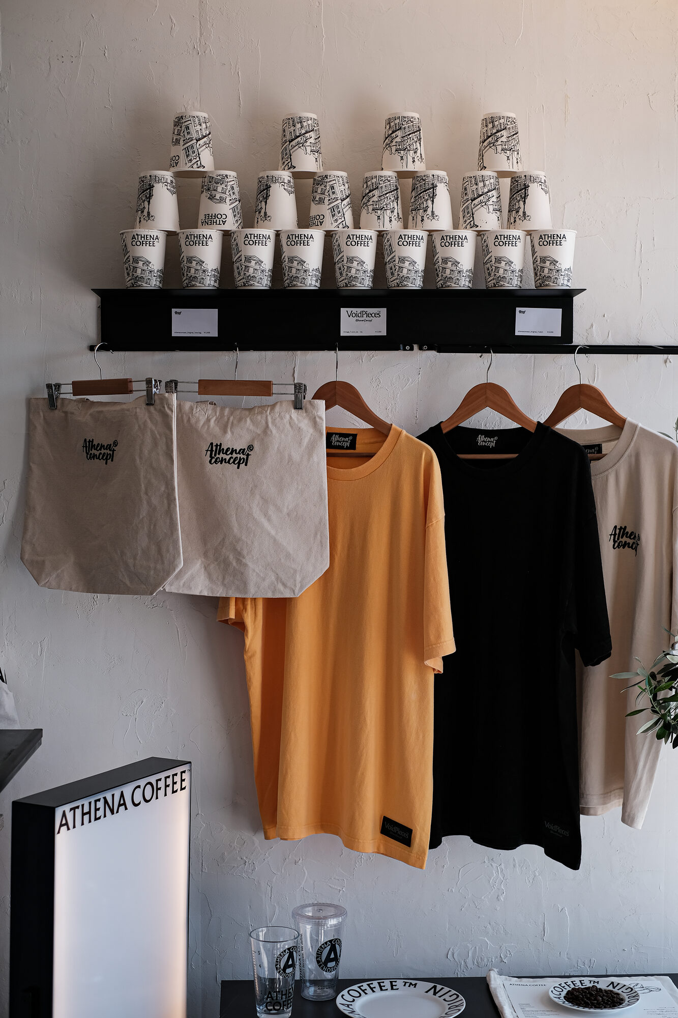 店内の物販什器 — カップ、トート、Tシャツ